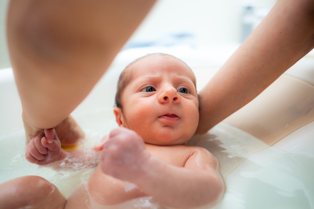 Image of a newborn in a bath. Warm baths are great for natural postpartum pain relief.